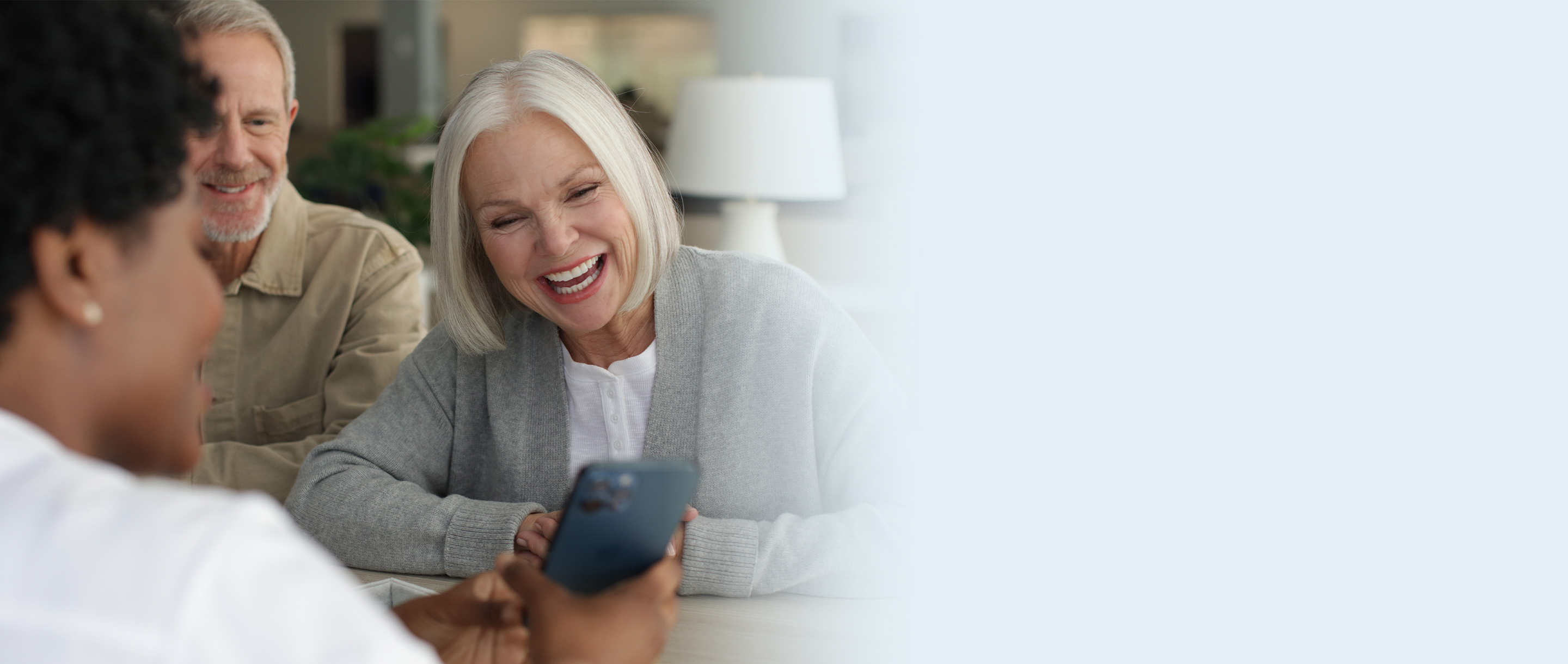 Hearing professional showing mobile device to female patient and male in background